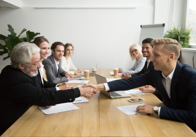 senior-investor-buying-startup-handshaking-young-entrepreneur-group-meeting